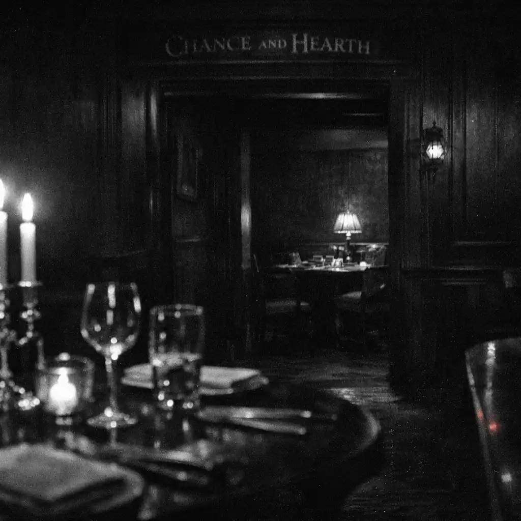 A candlelit dining table leading toward a dark passage at Chance and Hearth.